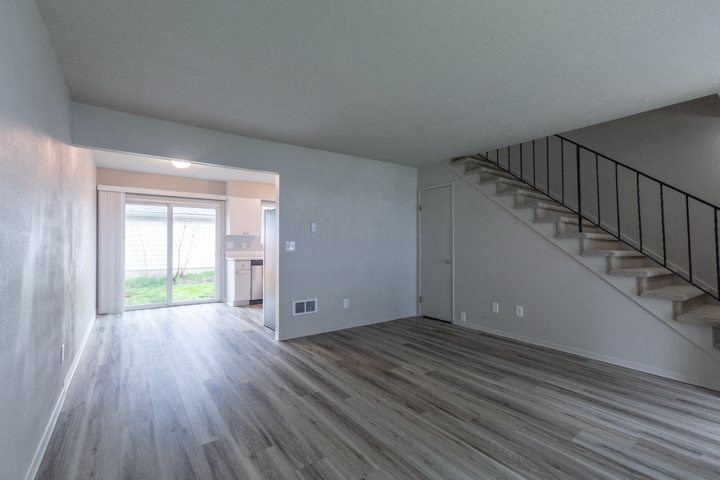 an empty living room with a staircase in the background