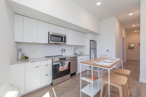 A modern kitchen with white cabinets and a wooden table.