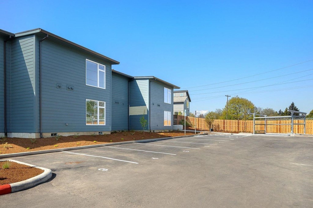 a blue building with a fence and a parking lot in front of it