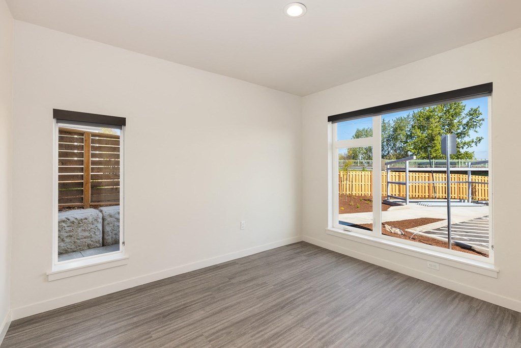 a bedroom with two large windows and a wooden fence