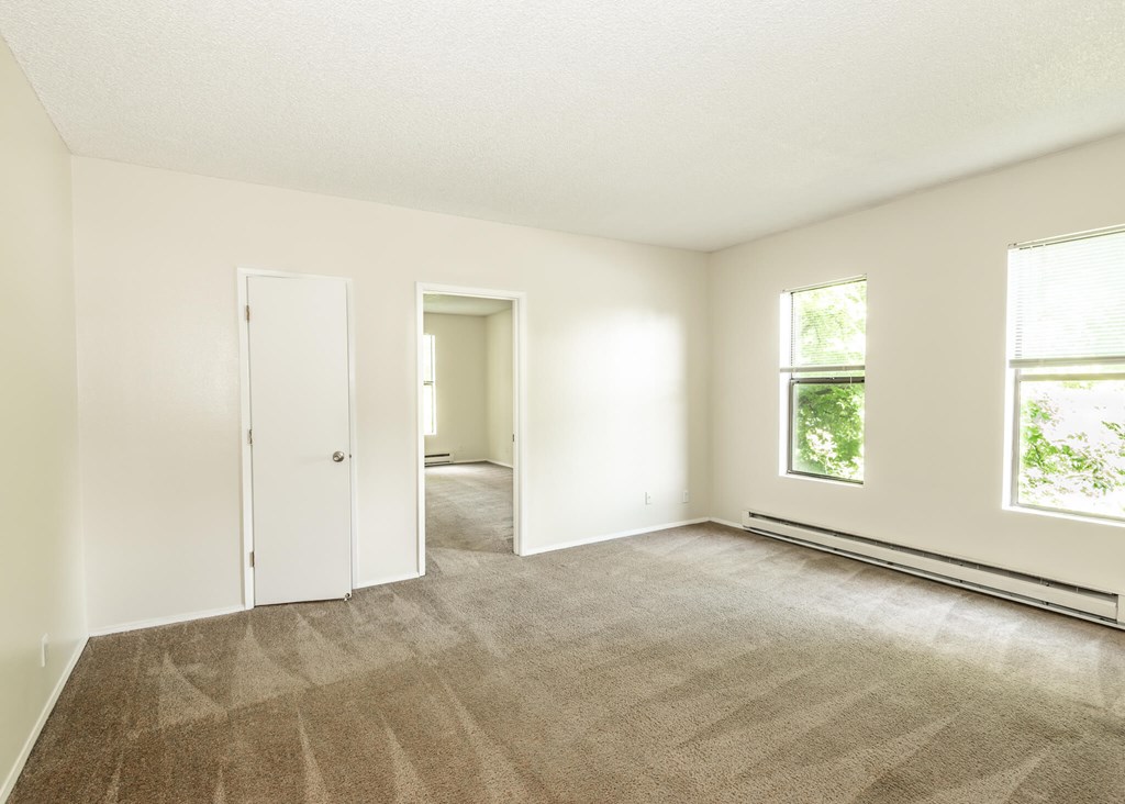 A room with carpeted floor and two doors.