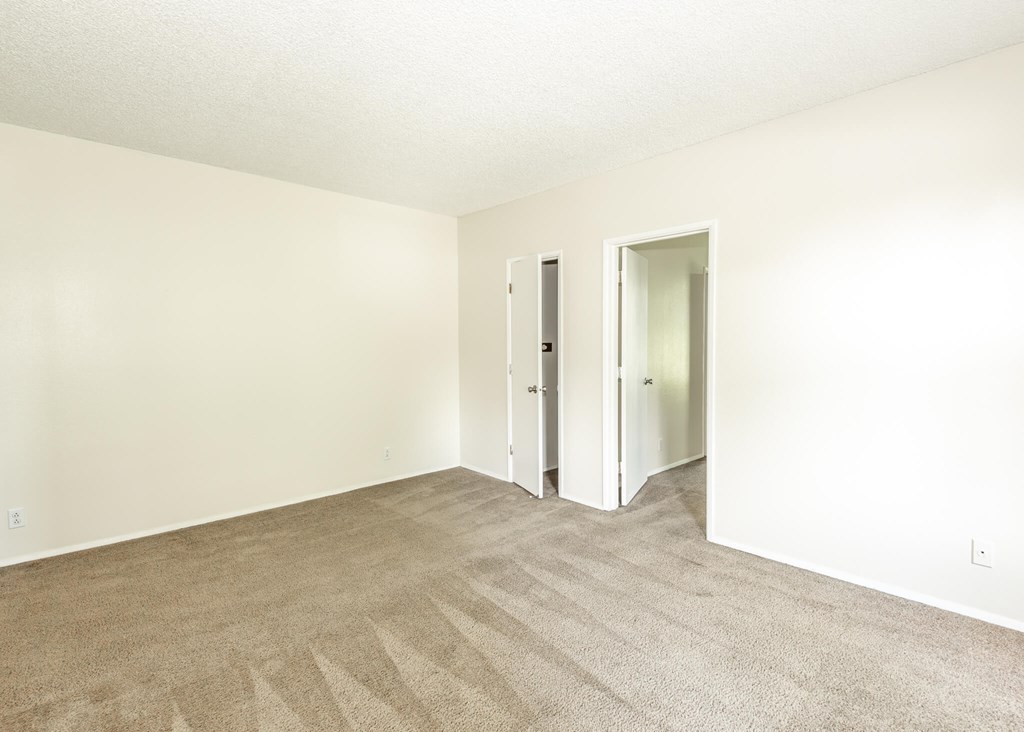 A room with carpeted floor and two doors.