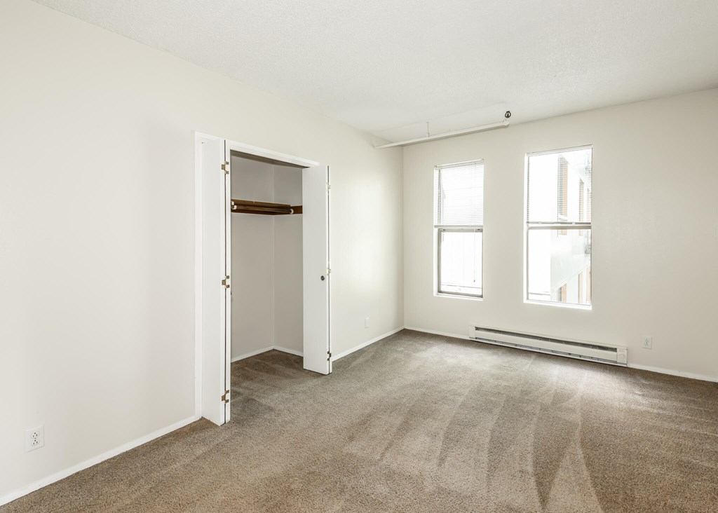 A room with a carpeted floor, two windows, and a door.