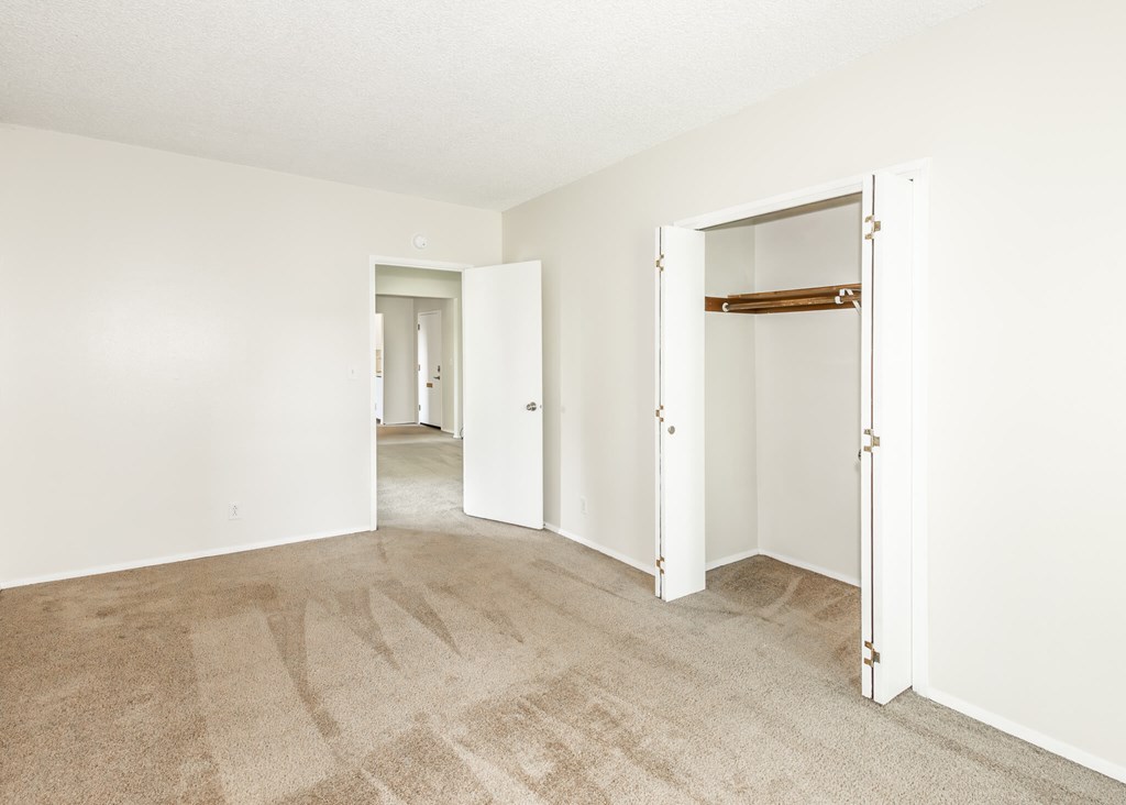 A room with a carpeted floor and two open doors.