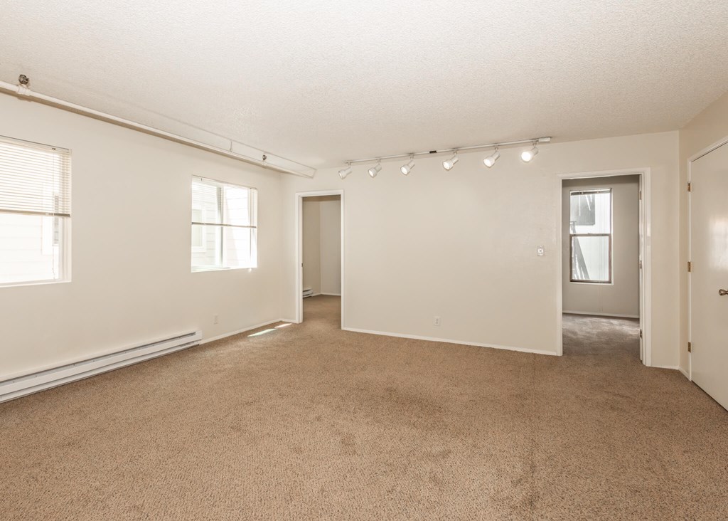 A large empty room with carpeted floor and white walls.