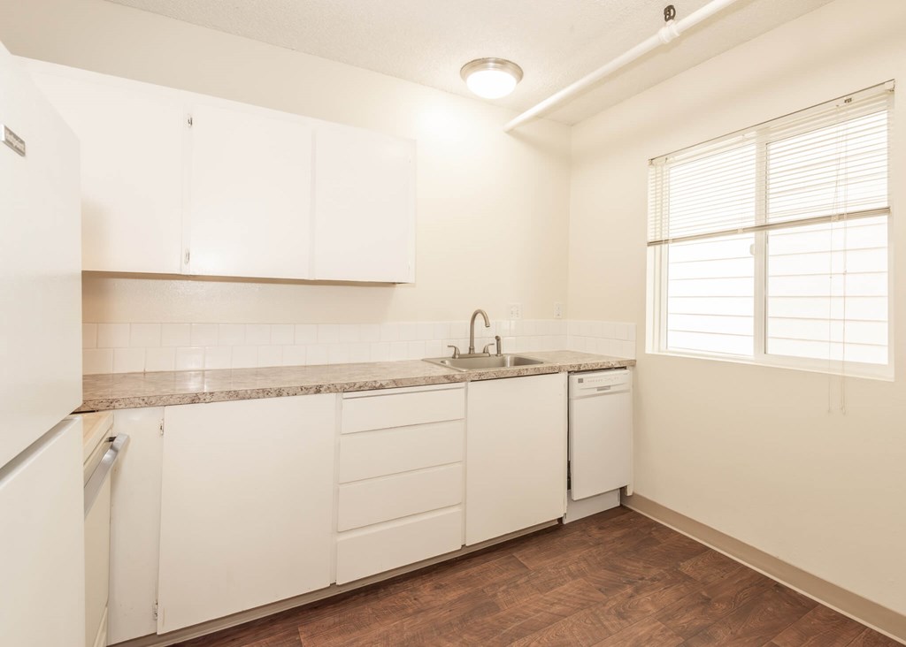 A kitchen with white cabinets and a granite countertop.