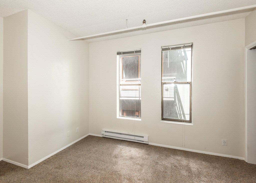 A room with a window and a carpet on the floor.
