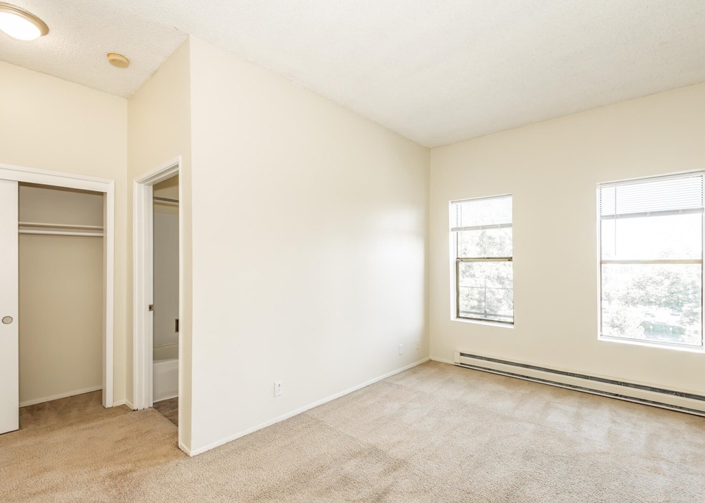 A room with a carpeted floor, a window, and a door.