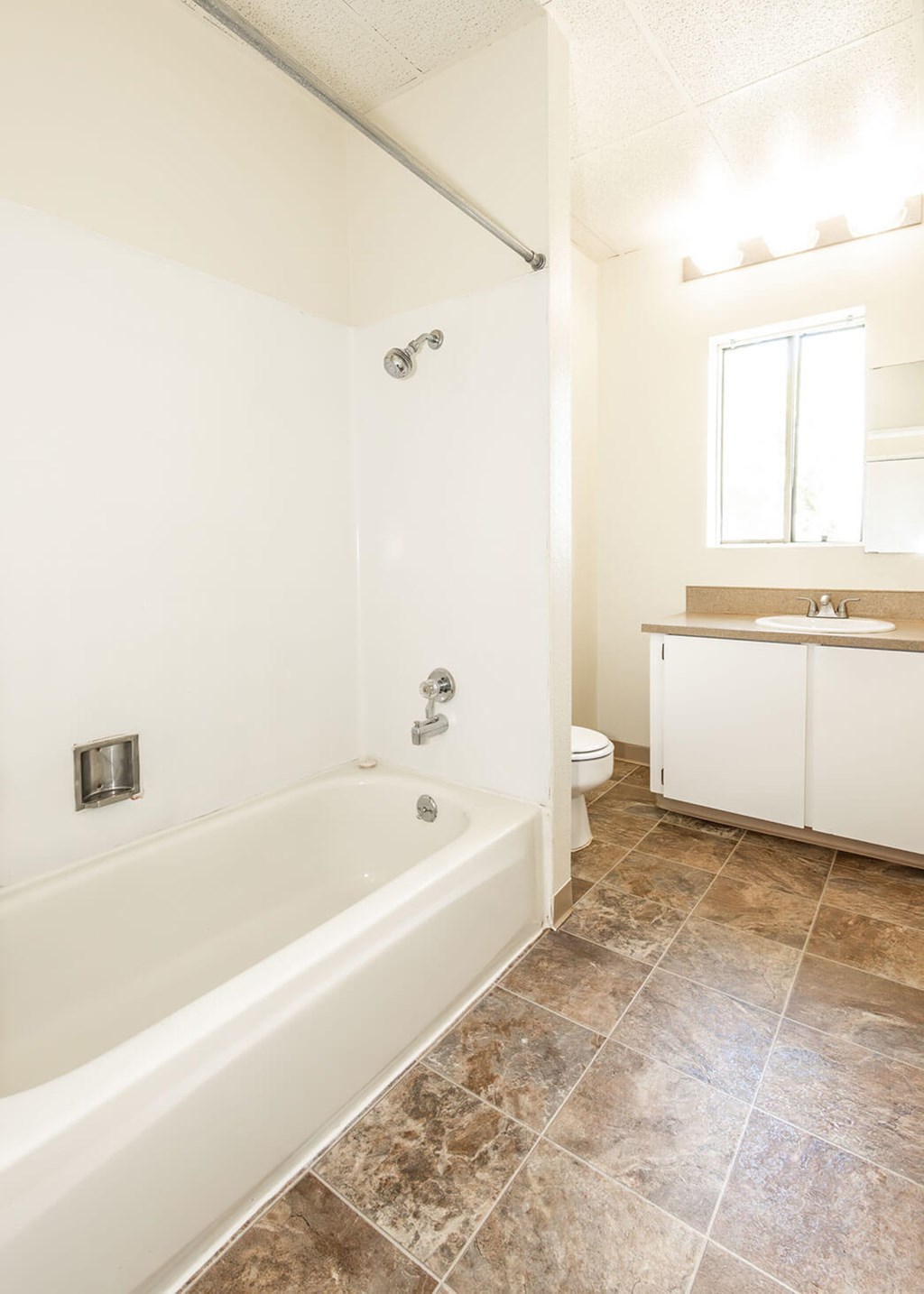 A white bathroom with a tiled floor and a bathtub.
