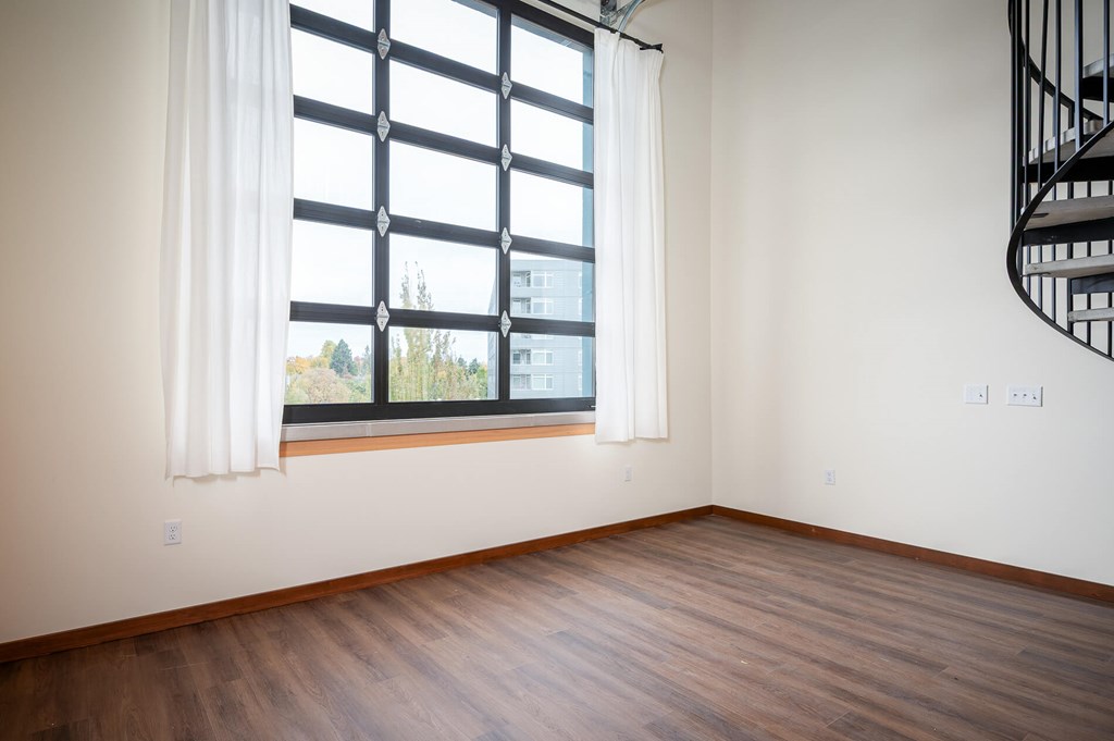 A room with a window and a spiral staircase.
