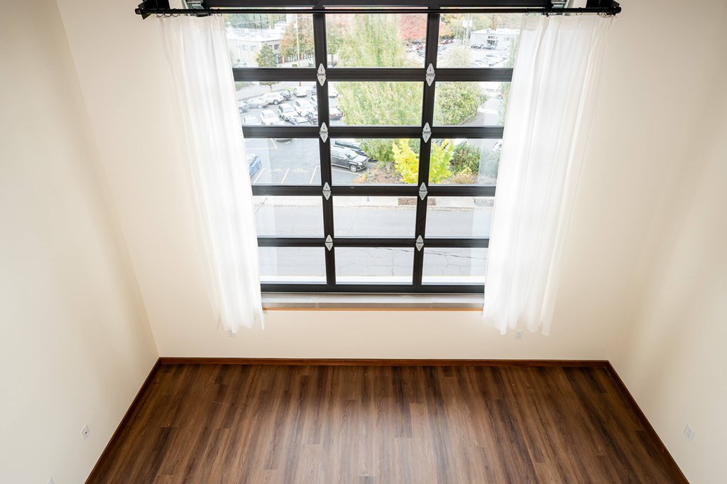 A room with a window overlooking a parking lot.