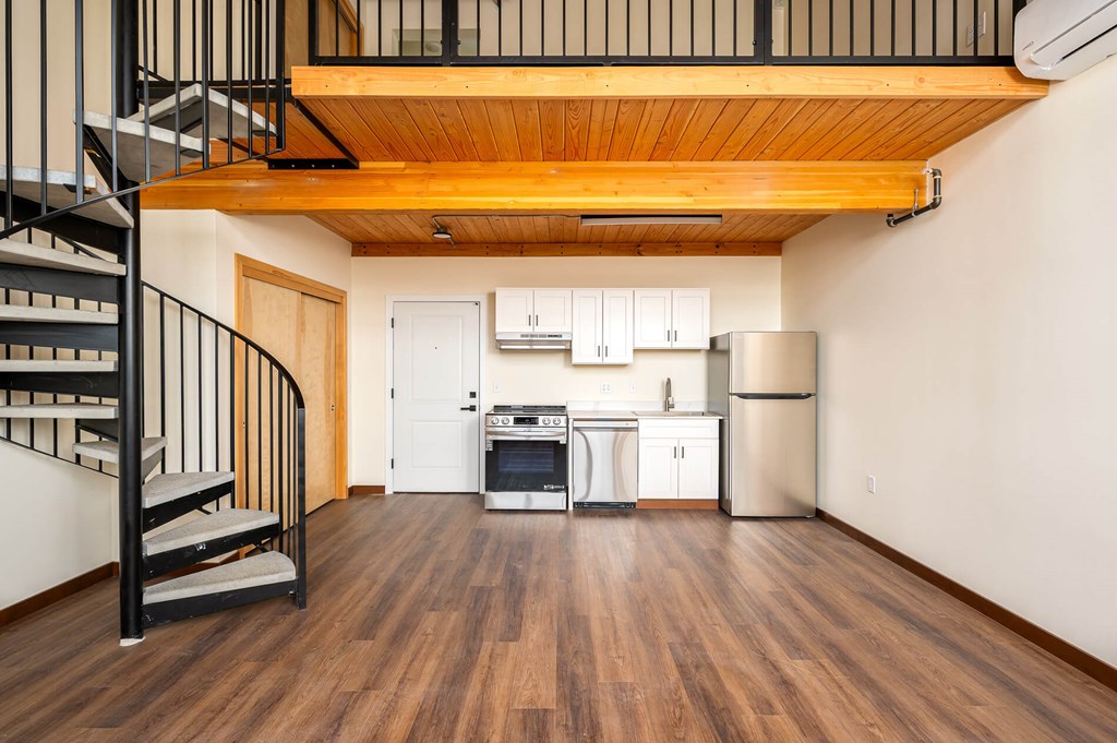 A kitchen with a staircase on the left side.