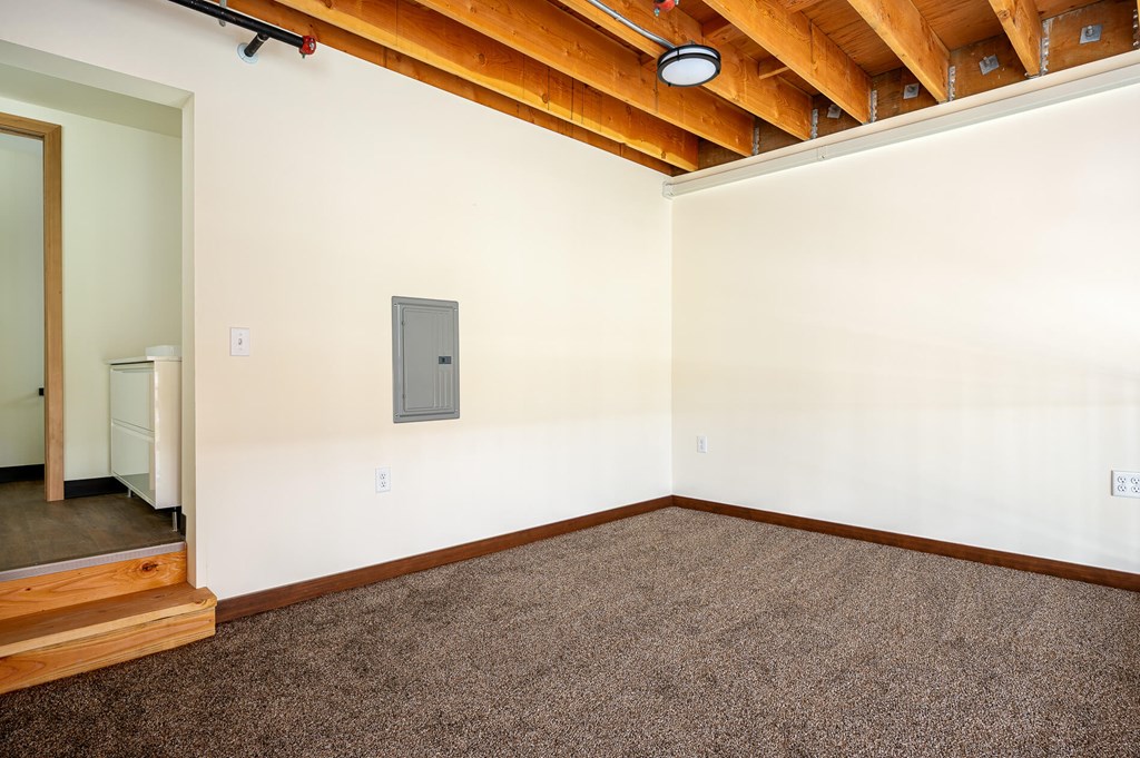 A room with a brown carpet and a wooden ceiling.