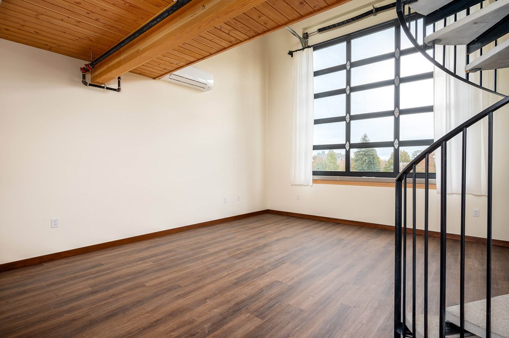 A room with wooden floors and a window with a view of trees.