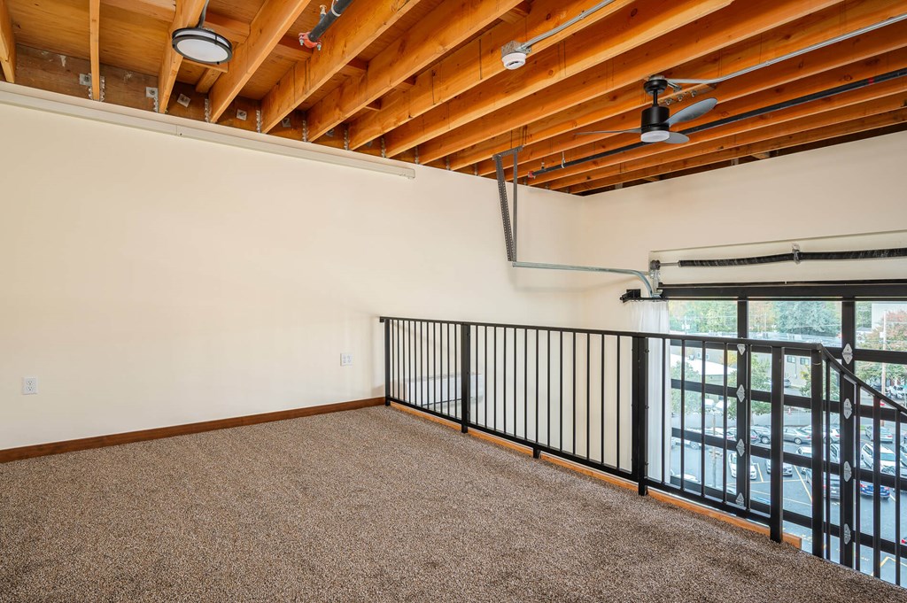 A room with a carpeted floor and a balcony with a railing.