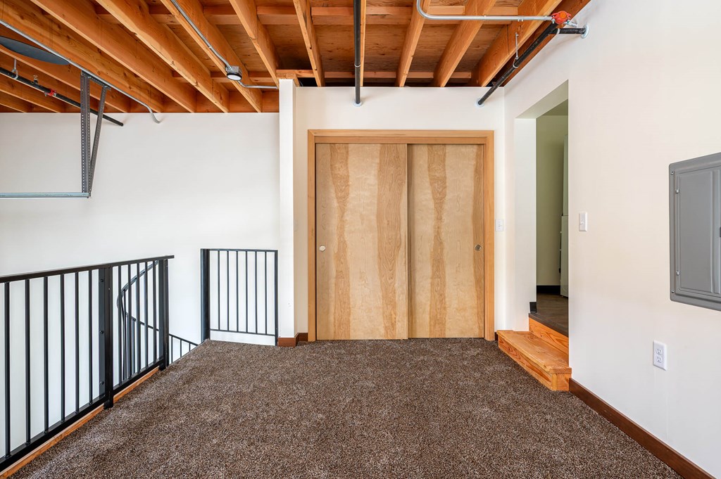 A room with a brown carpet and a wooden door.