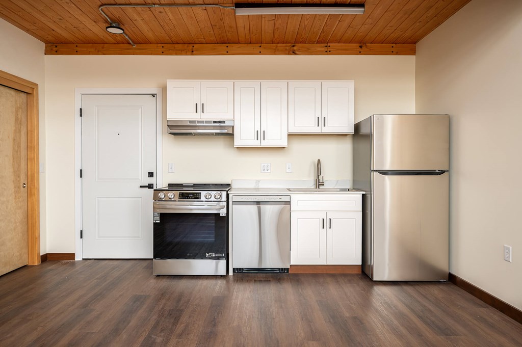 A kitchen with a stainless steel refrigerator, dishwasher, and oven.