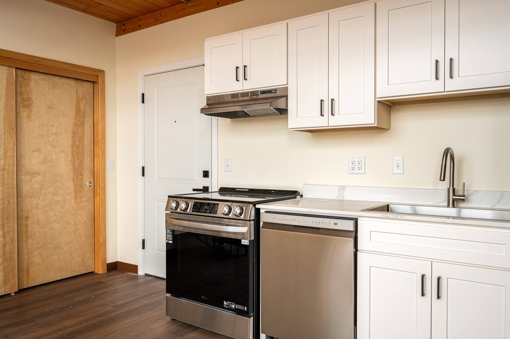 A modern kitchen with a stainless steel oven and white cabinets.