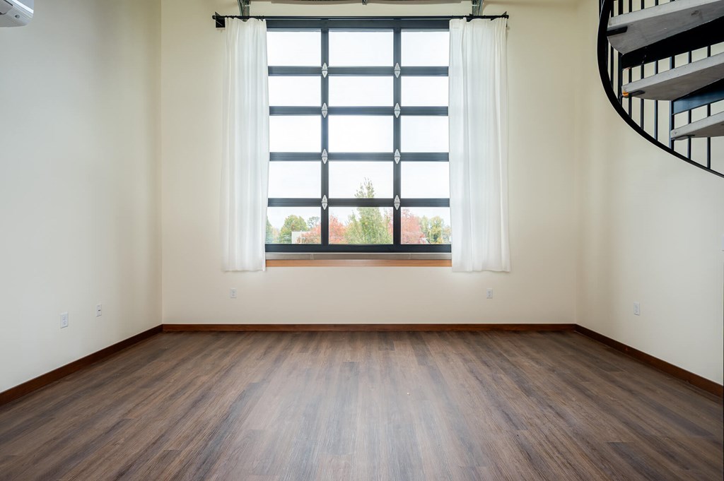 A room with a window and a spiral staircase.
