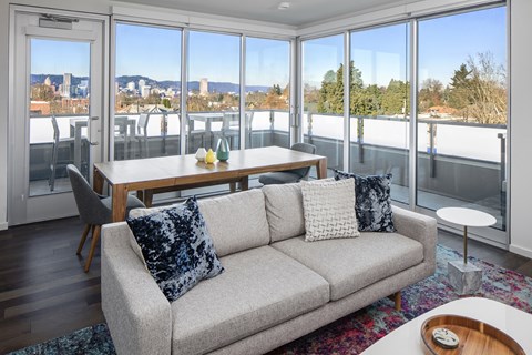 A living room with a grey couch and a table with a vase of flowers on it.