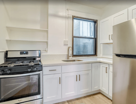 A modern kitchen with a stove, sink, and refrigerator.