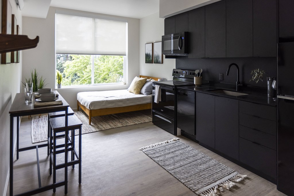 a kitchen and living room with a large window and black cabinets at Shift, Portland, OR 97217