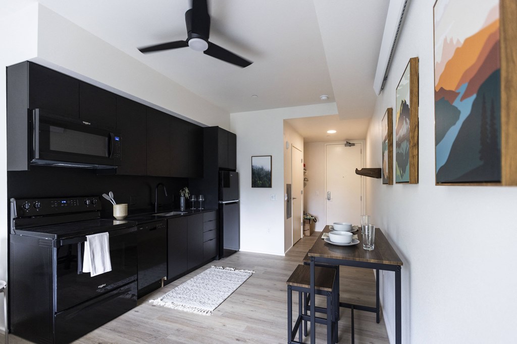 a kitchen and living room with black cabinets and a black stove and a counter top at Shift, Portland