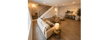 A well-lit living room with a white sofa and wooden floors.