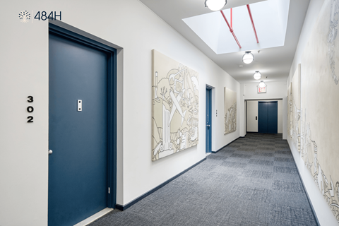 A hallway with a blue door and a white wall with a drawing on it.