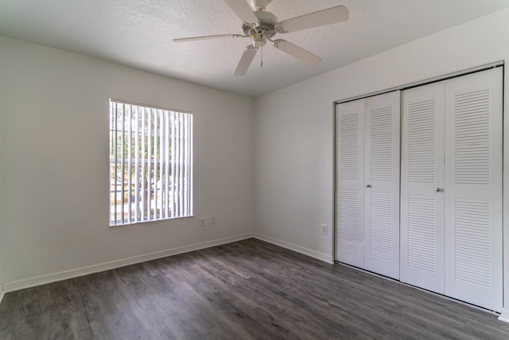 A room with a ceiling fan and a window with blinds.