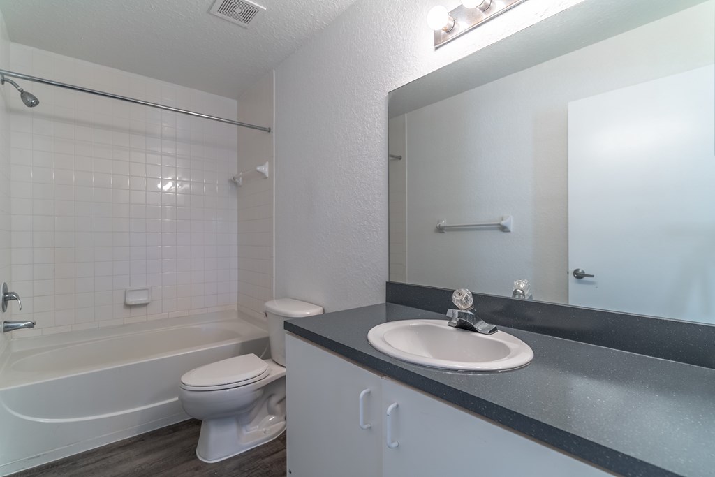 A white toilet sits in a bathroom next to a sink.