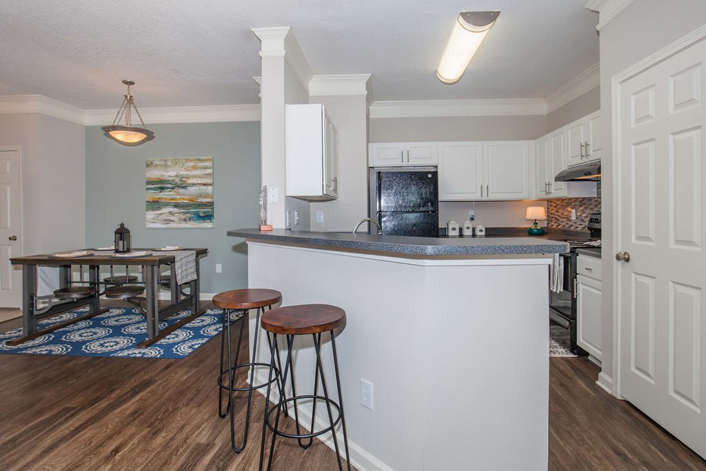 a kitchen with a counter top bar and stools at Carrington Place at Wildewood, Columbia, SC 29223  
