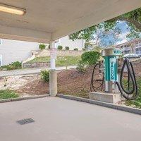 A gas pump is located under a roof next to a concrete pillar.