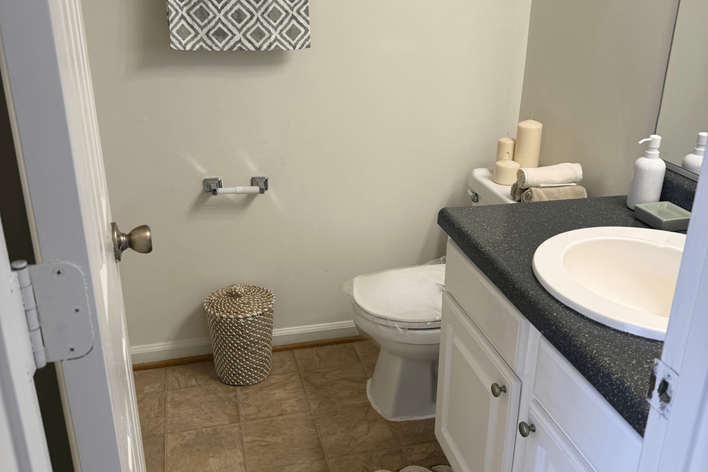 A bathroom with a toilet, sink, and trash can.