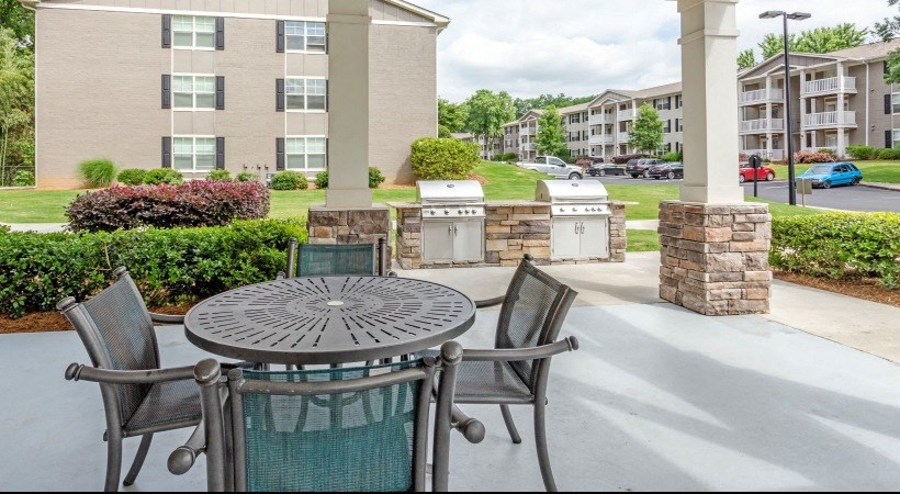 a patio with a table and chairs in front of an apartment complex