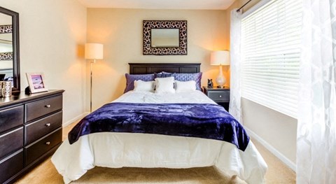 a bedroom with a large bed and a window with blinds at The Bristol Apartments, Greenville