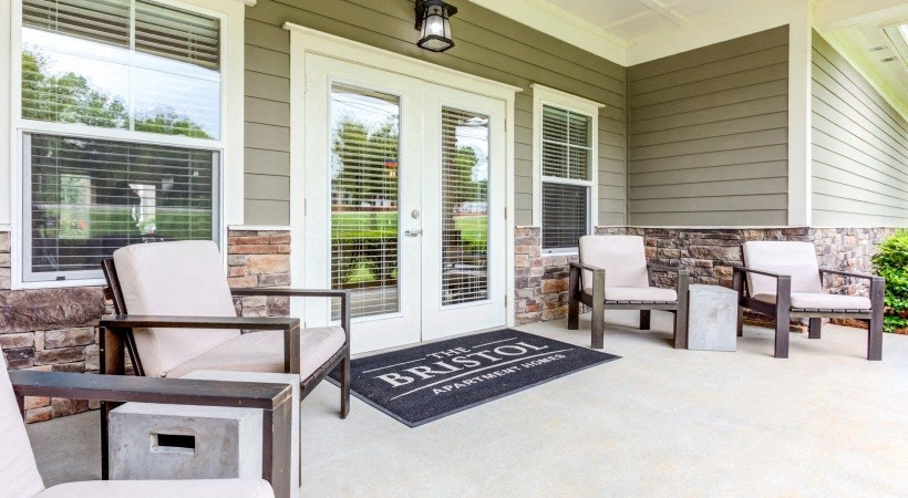 a patio with chairs and a rug in front of a door