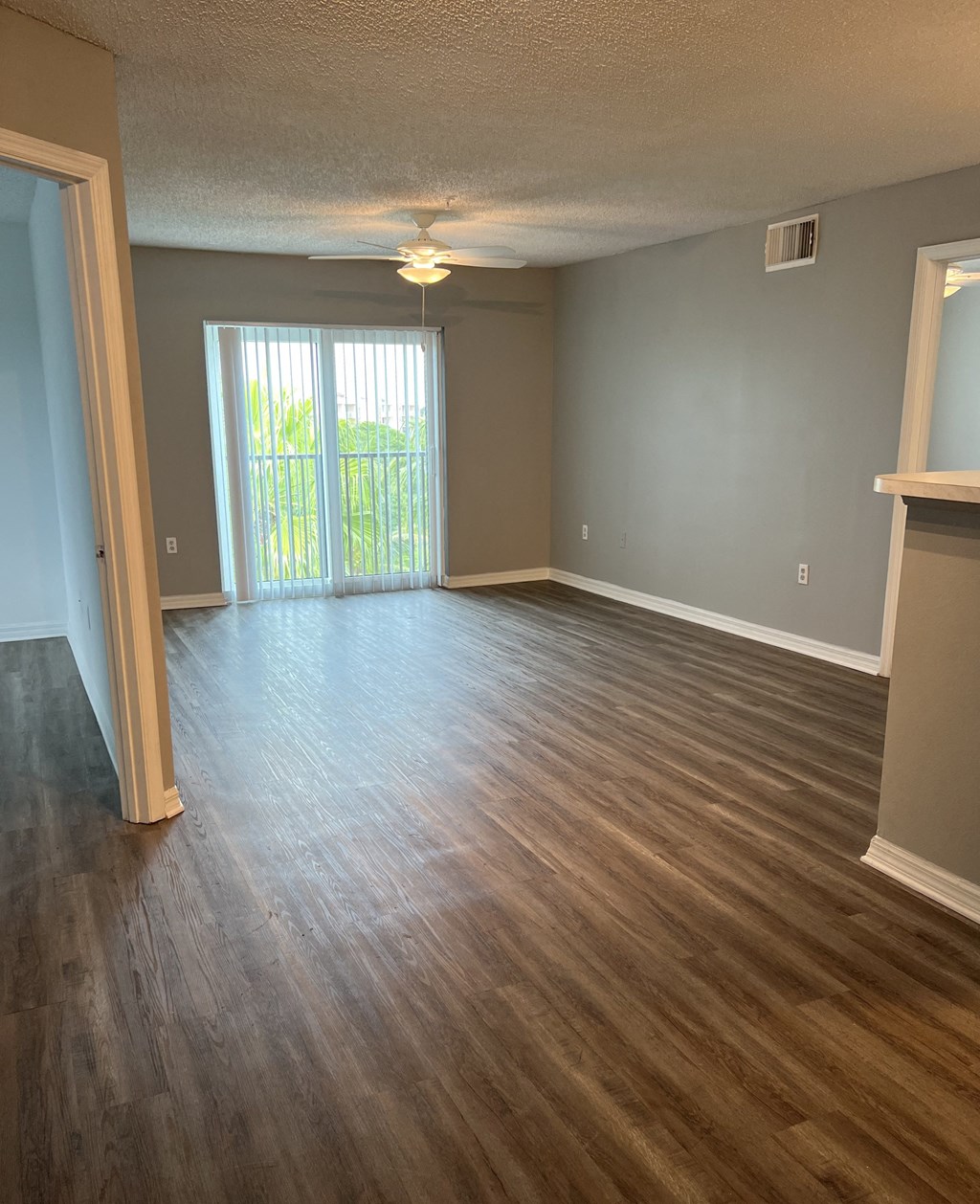 an empty living room with wood floors and a sliding glass door