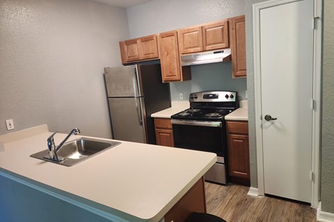 A kitchen with a stove, sink, and cabinets.