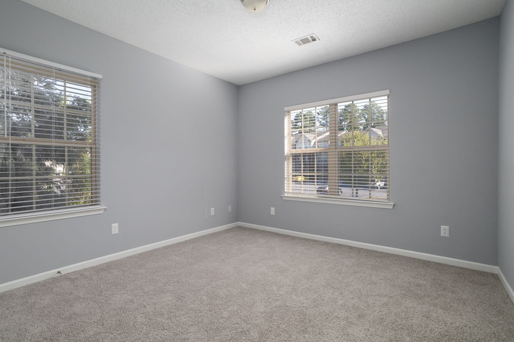 a bedroom with two windows and a carpeted floor