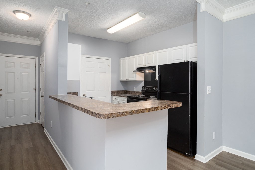 a kitchen with an island and a black refrigerator