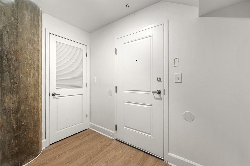 A white door with a window is in a room with wood flooring.