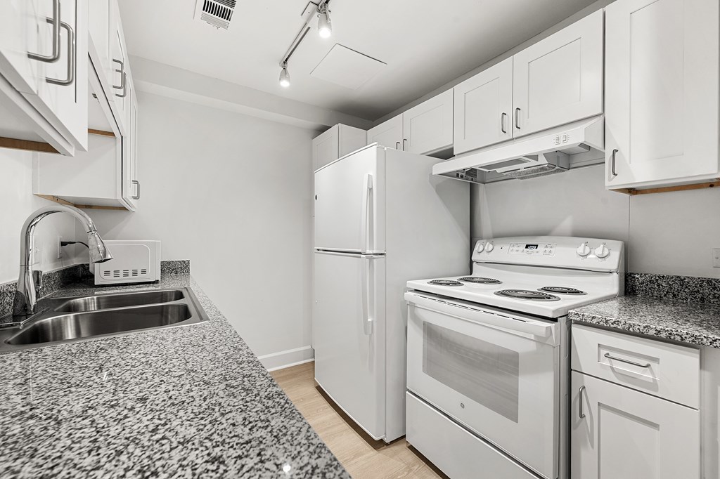 A kitchen with white appliances and a granite countertop.