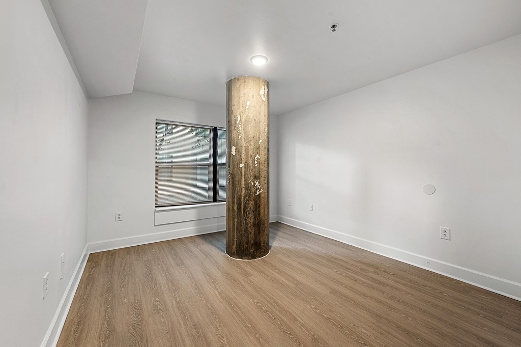 A room with a wooden floor and a large wooden pillar.