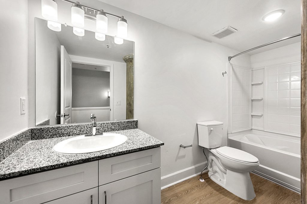 A white toilet sits in a bathroom next to a sink and a mirror.