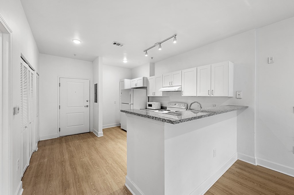 A kitchen with white cabinets and a wooden floor.