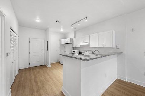 A kitchen with white cabinets and a wooden floor.