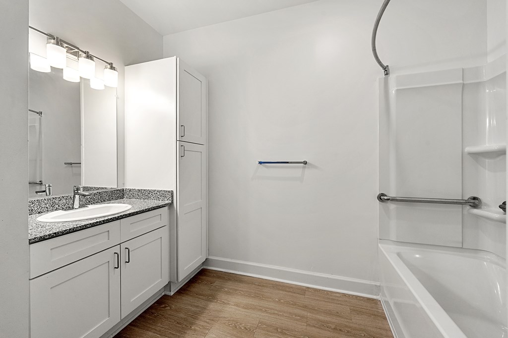 A white bathroom with a sink, mirror, and bathtub.