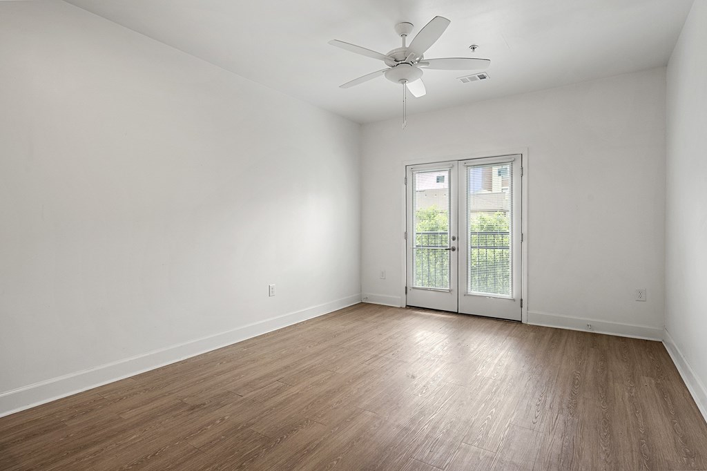 A room with a ceiling fan and sliding glass doors.
