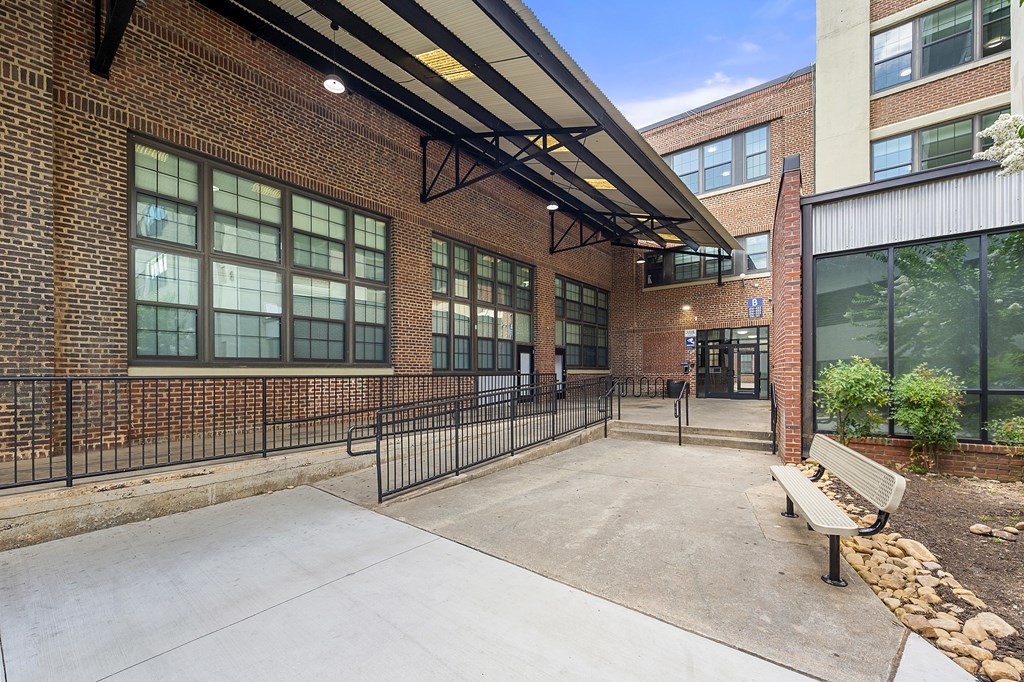 A brick building with a black fence and a bench in front.